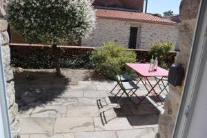 a pink table and chairs on a stone patio at Chambre, entrée indépendante, SDB privée in Cugand