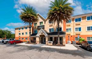 a hotel with palm trees in a parking lot at Southpoint Suites Jacksonville in Jacksonville