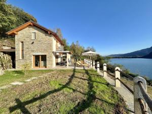 a stone house with a fence next to a lake at Perla di Mergozzo 1 in Mergozzo