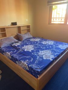 ein Bett in einem Zimmer mit einer blau-weißen Decke in der Unterkunft Mona chalet in Adschlun