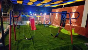 ein Spielplatz mit Schaukeln in einem Raum mit Gras in der Unterkunft Mona chalet in Adschlun