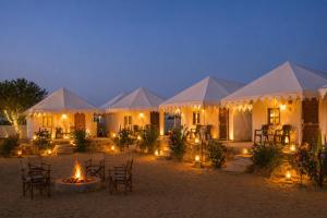 a group of tents with chairs and a fire in front of them at Sky Desert Safari Jaisalmer & Spa in Jaisalmer