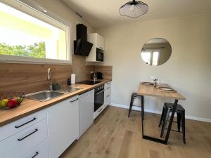 a kitchen with white cabinets and a sink and a mirror at Charmant studio proche du centre-ville in Orange +5 photos