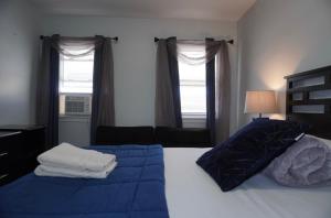 a bedroom with a bed with blue comforter and two windows at West New York room 14 in West New York