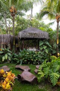 a garden with a gazebo with a grass roof at Pousada Nativa in Caraíva