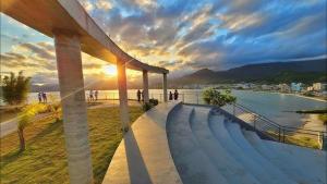 a group of people walking on a sidewalk next to a body of water at Sobrados Novos Litoral Norte Caraguatatuba, a 150 m a pe da Praia das Palmeiras, Ar condicionado, WiFi gratis, Churrasqueira privativa, Pet friendly, Estacionamento in Caraguatatuba