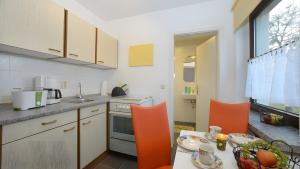 a kitchen with orange chairs and a table with food on it at Ferienwohnung Brunk in Altefähr