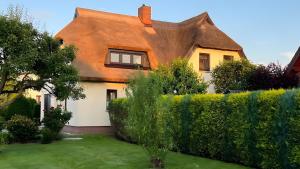a house with a thatched roof and a yard at Ferienwohnung Brunk in Altefähr