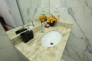 a sink in a bathroom with flowers on a counter at Pousada House Garden in Goiânia +22 photos
