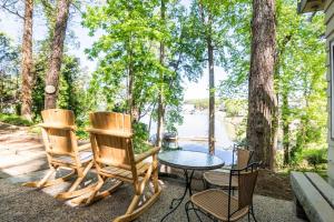 a patio with chairs and a table with a view of a lake at Waterfront Cottage, Fiery Sunsets in Charlotte