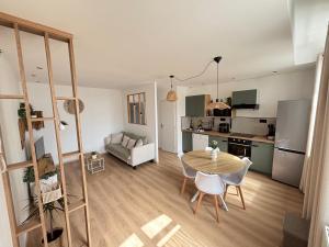 a kitchen and a living room with a table and chairs at Le Cocon des Remparts in Gravelines