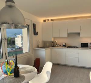 a kitchen with white cabinets and a table and chairs at L4K3 Luxury Apartment - Lake View, Free Pool, Balcony, 50 m to Lake & Historic Center, 90 m2 in Pisogne