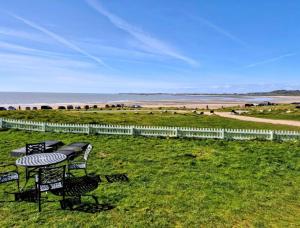 a table and chairs in a field with the beach at The Blue Dolphin with Panoramic Sea Views in Tythegston