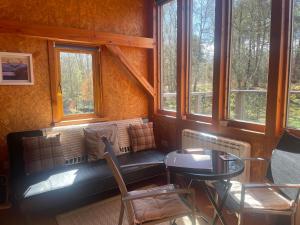a room with a bench and a table and windows at Caledonian Glamping in Cannich