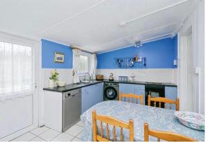 a kitchen with blue walls and a table and chairs at The Blue Dolphin with Panoramic Sea Views in Tythegston +18 photos