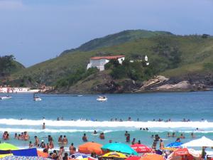 a group of people on a beach with people in the water at Loft Aloha in Cabo Frio