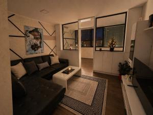 a living room with a black couch and a table at Ninche's Penthouse - free private parking in Pljevlja
