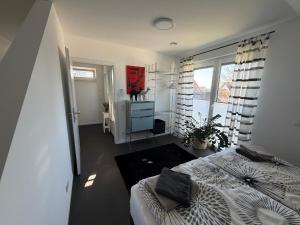 a white bedroom with a bed and a window at Moderne Ferienwohnung über 2 Etagen in Bissendorf