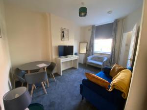 a living room with a blue couch and a table at Cute Central House Sleeps 4 in Stafford