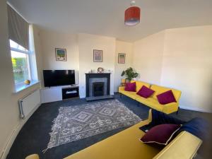 a living room with a yellow couch and a fireplace at Town Centre House Sleeps 8 with parking in Stafford