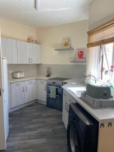 a kitchen with white cabinets and a washing machine at Town Centre House Sleeps 8 with parking in Stafford