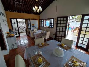a dining room with a table and chairs and windows at Pousada Nova Flor de Lotus Suites in Tamandaré