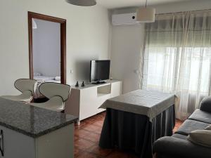 a living room with a couch and a table and a tv at Ático luminoso con terraza privada in Sanlúcar de Barrameda