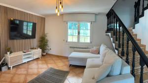 a living room with a white couch and a tv at Villa Playa Covelo in Pontevedra