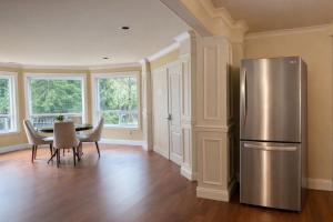 a kitchen with a stainless steel refrigerator and a table at Hampton Luxe House in Coquitlam