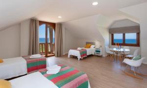 a hotel room with two beds and a table and chairs at Casa do Seixo in Oia +31 photos