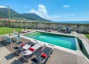 a swimming pool with chairs and a table and the ocean at Casa do Seixo in Oia