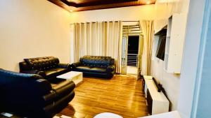 a living room with two black leather couches at Montana Stay B&B in Ruhengeri