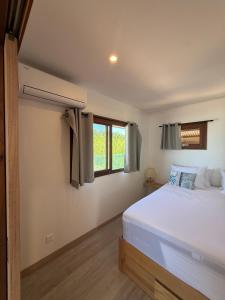 a bedroom with a white bed and a window at Le TeRava - Beach House in Ataiti