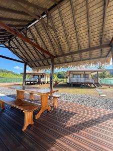 a picnic table under a straw roof on a deck at Le TeRava - Beach House in Ataiti