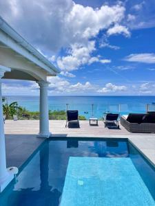 a swimming pool with a view of the ocean at Villa d'Happy Bay - Panoramic View of Caribbean and sunsets in Friar's Bay
