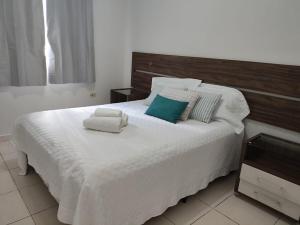 a bedroom with a large white bed with towels on it at Aconchego 3 - Self Check-in in Presidente Prudente