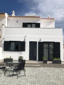 a white house with black doors and a table and chairs at Casa Dulcelina Monte Gordo, Algarve, Portugal in Monte Gordo