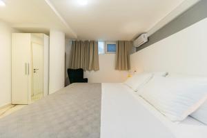 a bedroom with a large white bed and a chair at CentRooms Kovac1 in Zadar