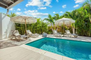 a swimming pool with two umbrellas and two chairs at Walk to Beach - Private Pool Villa in Palm-Eagle Beach