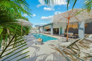 a resort with a swimming pool with chairs and an umbrella at Walk to Beach - Private Pool Villa in Palm-Eagle Beach
