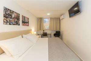 a hotel room with a white bed and a desk at CentRooms Kovac1 in Zadar +25 photos