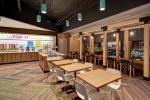 a restaurant with wooden tables and chairs and a counter at Tru By Hilton Raleigh Durham Airport in Morrisville