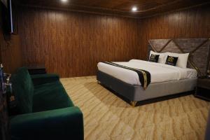 a bedroom with a large bed and a green chair at The Barcelo Apartment & Cottages in Naran