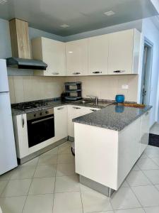 a kitchen with white cabinets and a counter top at Appartement le jasmin in Hammamet +13 photos