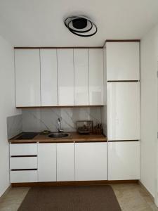 a kitchen with white cabinets and a sink at Apartmani Edi Ulcinj in Ulcinj
