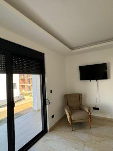 a living room with a chair and a flat screen tv at Apartmani Edi Ulcinj in Ulcinj