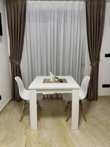a white table and chairs in a room with curtains at Apartmani Edi Ulcinj in Ulcinj +7 photos