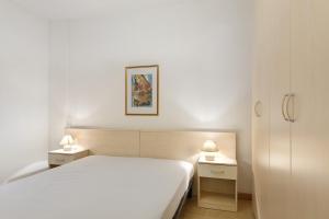 a bedroom with a white bed and two night stands at Tabià Padola in Padola