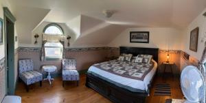 a bedroom with a bed and two chairs and a window at Bugaboo Cottages in Summerside