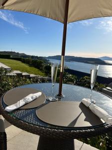 a table with two wine glasses and an umbrella at Tigh Beag Pod with Hot Tub in Oban